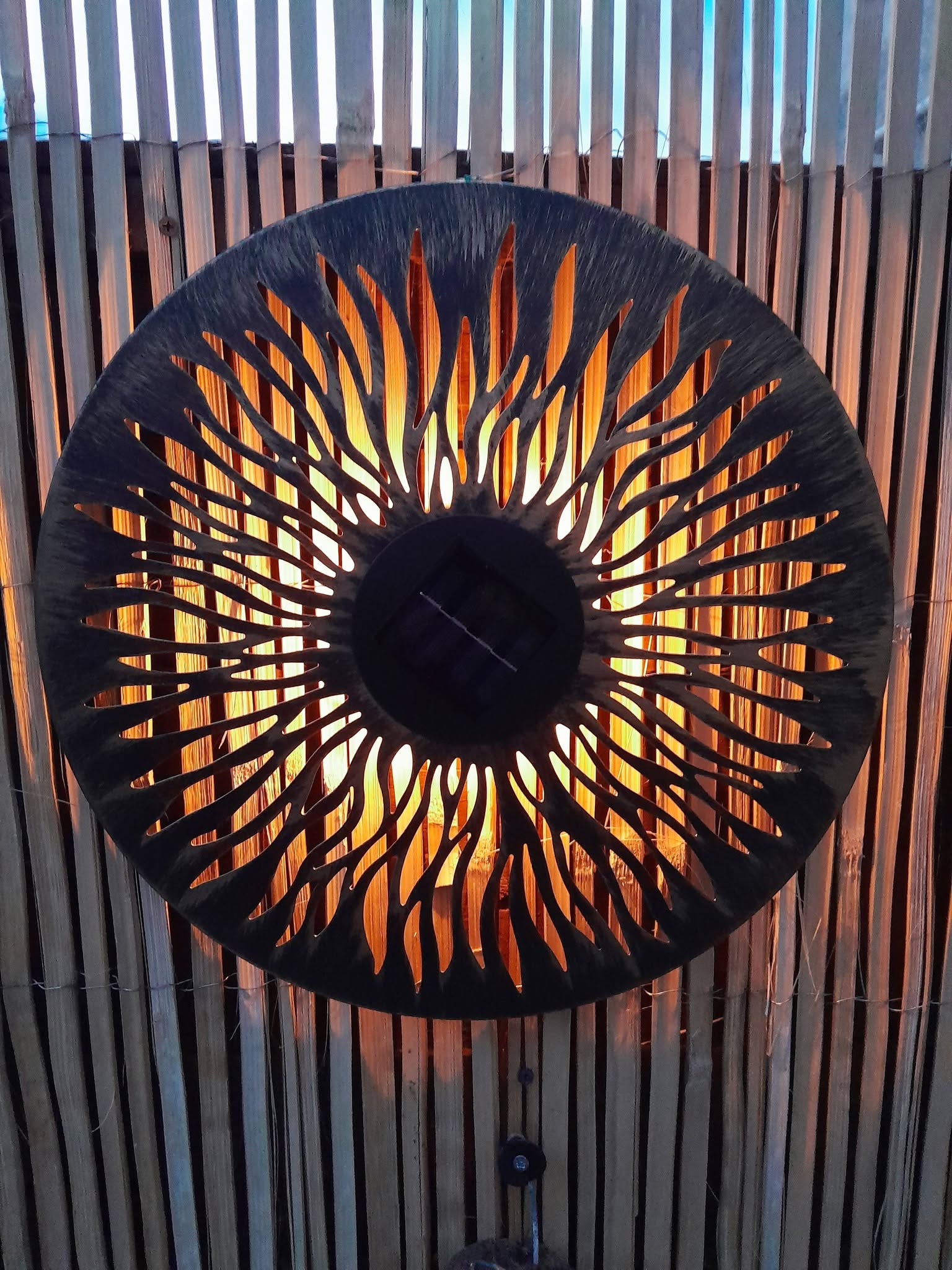 Circular metal art installation with fire-like pattern