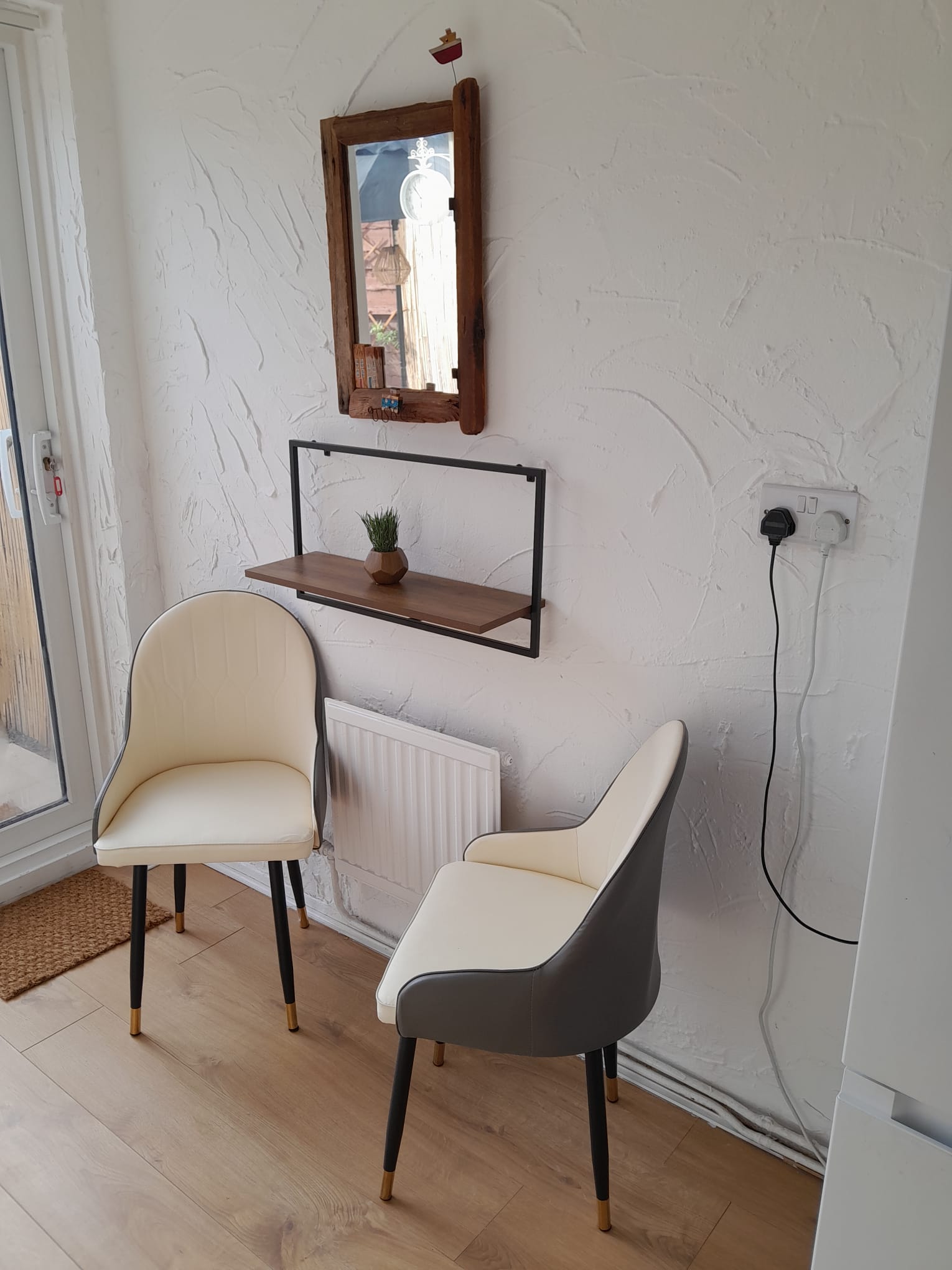 Two cream accent chairs beneath a driftwood mirror and shelf