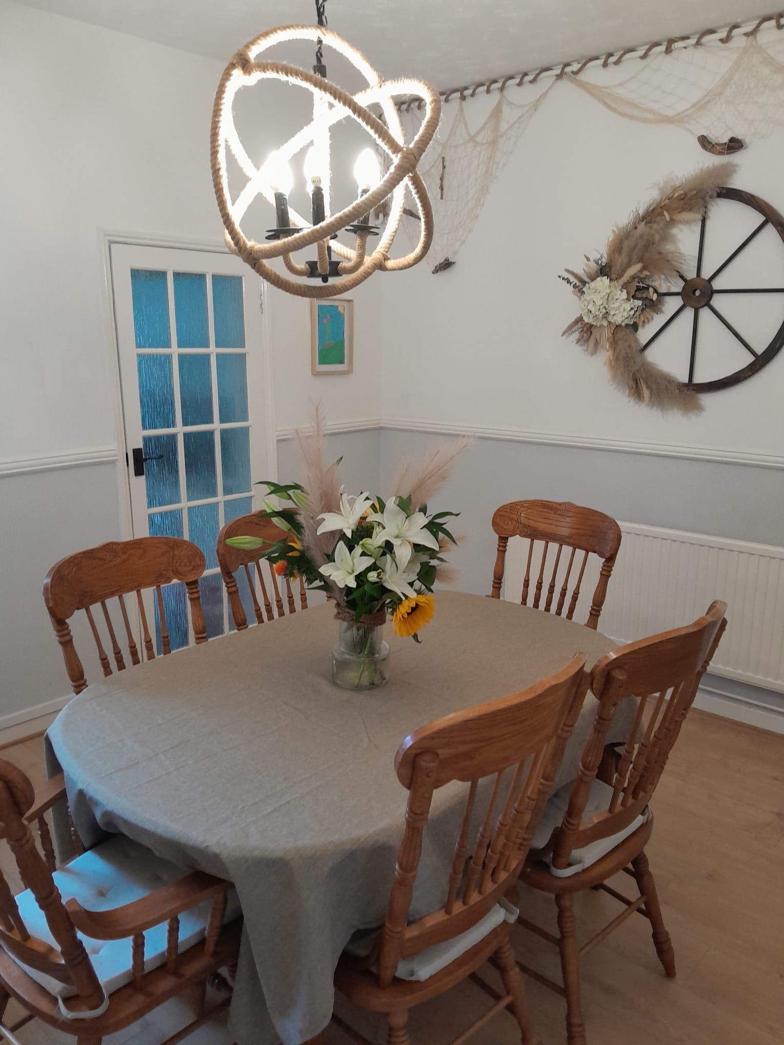 Coastal-themed dining room with a set table and rope chandelier
