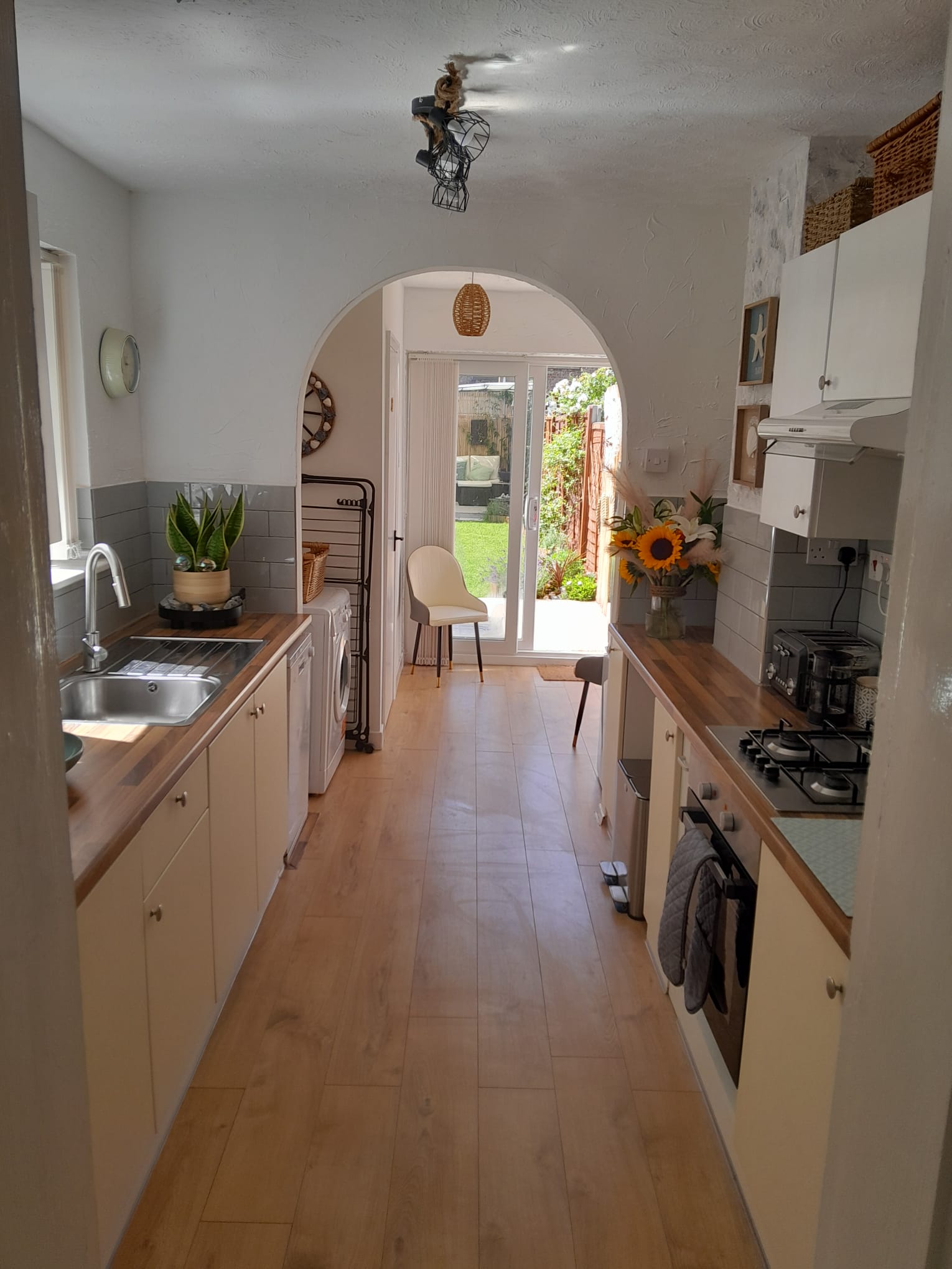 Bright galley kitchen leading through an archway to the garden