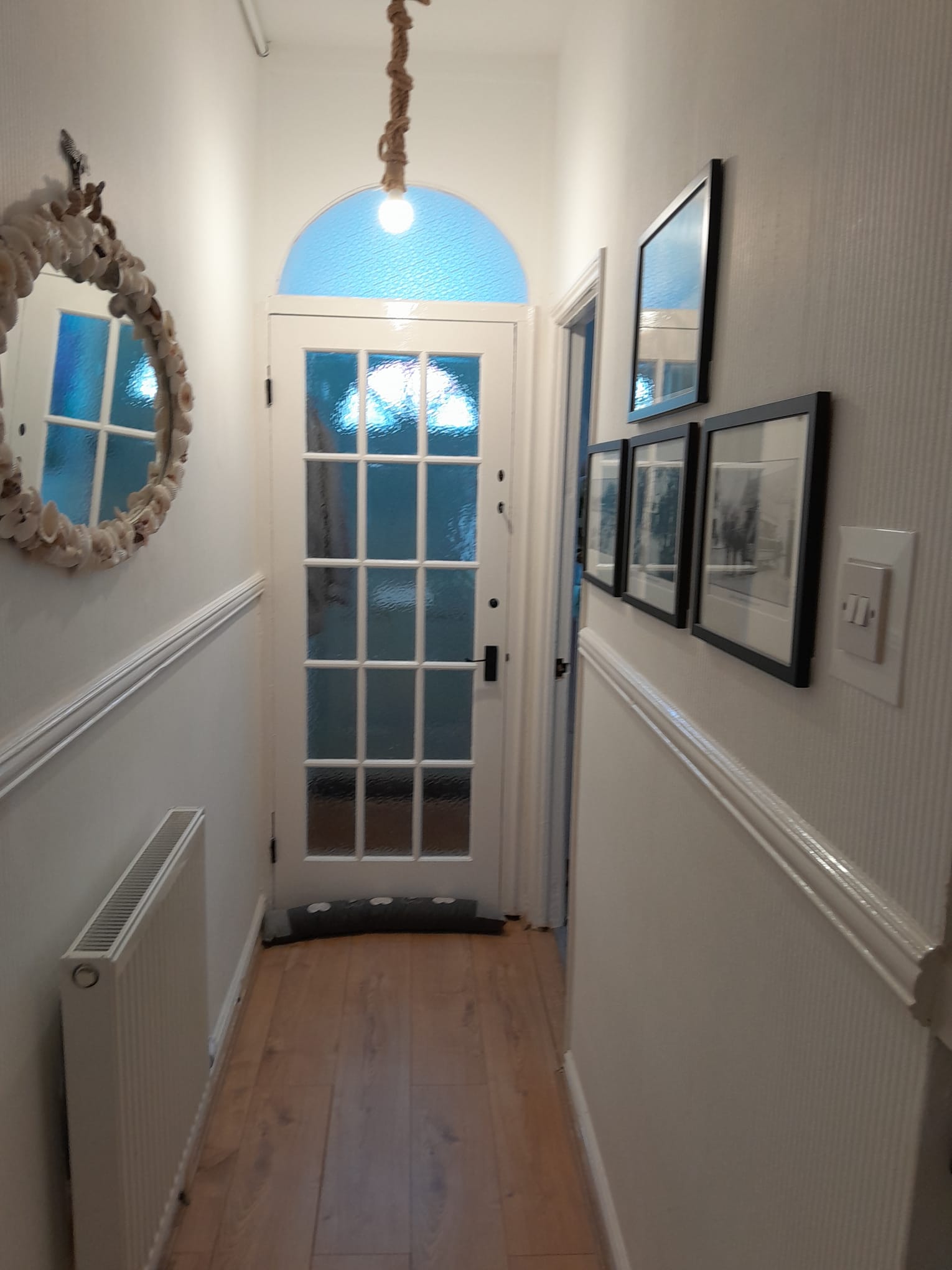 Bright Victorian hallway with glazed door and framed prints