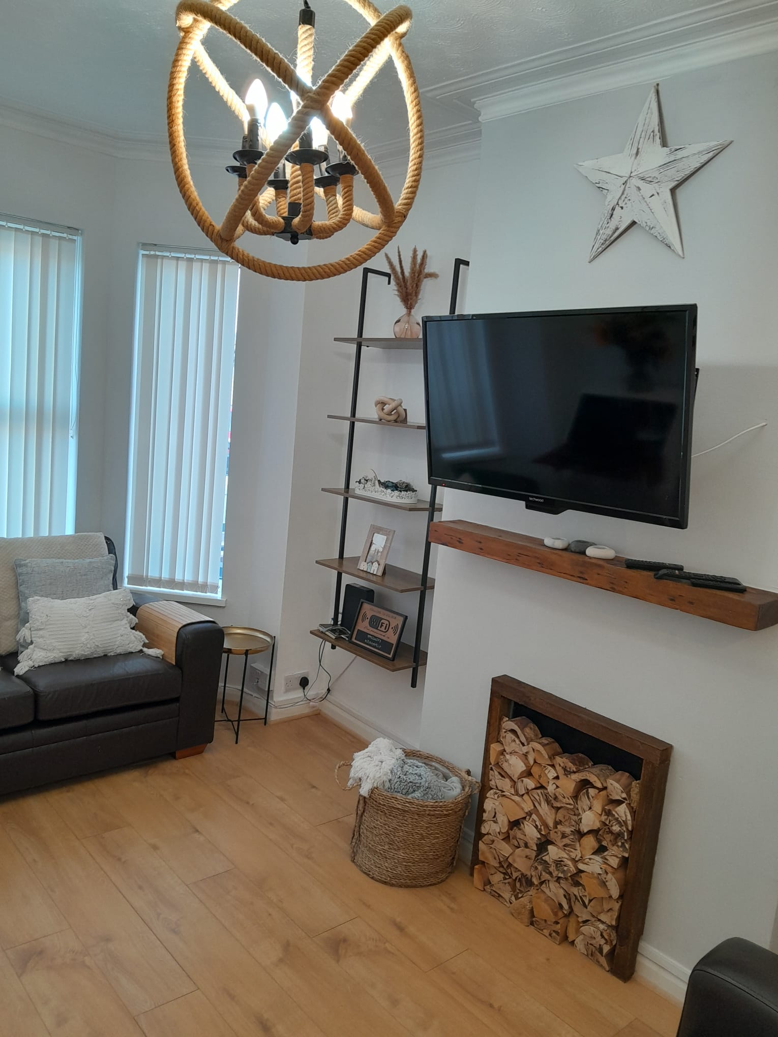 Comfortable living room with sofa, log store and rope chandelier