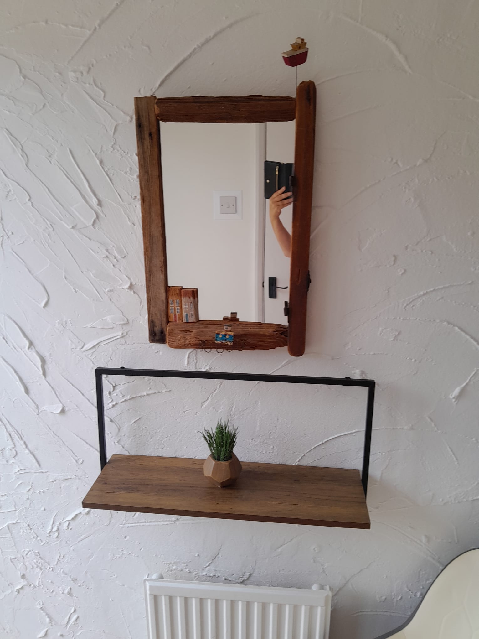 Rustic driftwood mirror above a floating shelf